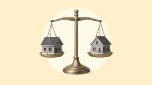 Two houses being weighed side-by-side on a balance scale over a yellow background