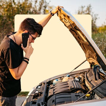 Person looking under hood of car while on phone