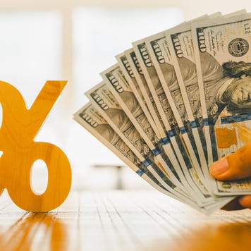 Percent symbol with people holding money that is many dollar bills. Concepts of the banking system, rising interest rates, inflation, deflation, and savings.