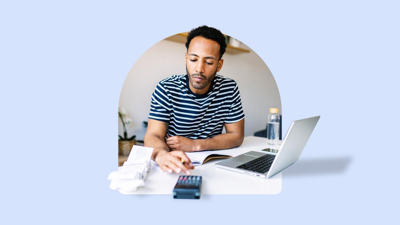 Man with laptop on table in front of him using calculator