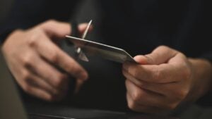 Young man cutting credit card with scissors