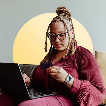 Seychelle Thomas sitting with laptop holding credit card