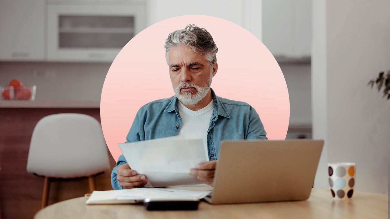 Older man looks at piece of paper at table.
