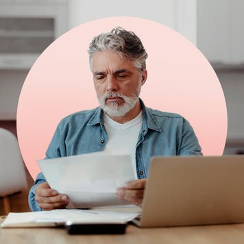 Older man looks at piece of paper at table.