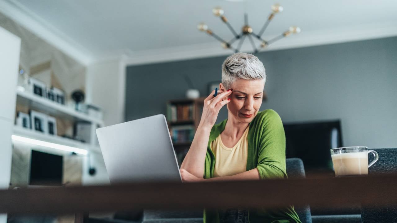 Businesswoman using laptop and documents, drinking coffee. Looking concentrated
