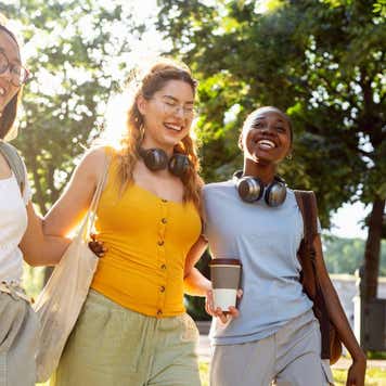 Group of modern young multiracial female friends, an University students, walking through the campus park