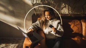 Woman sitting with laptop and holding credit card