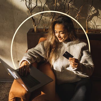 Woman sitting with laptop and holding credit card
