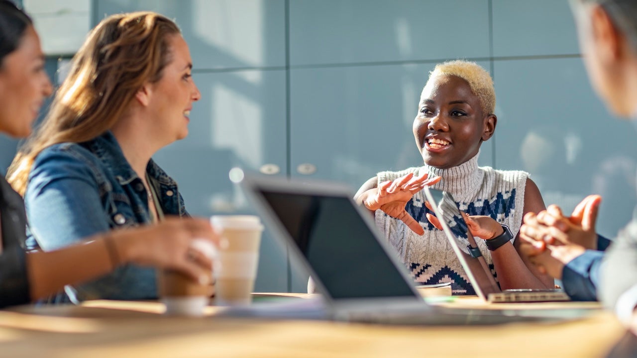 A business meeting led by a young Black woman with bleached hair.