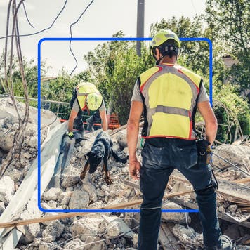 Emergency aid workers sifting through debris of a building