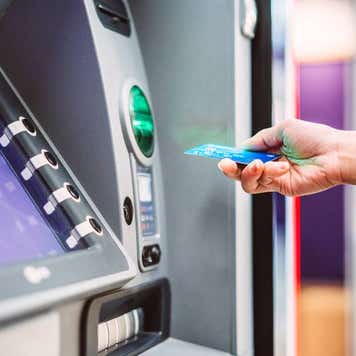 Female hand inserting bank card into ATM