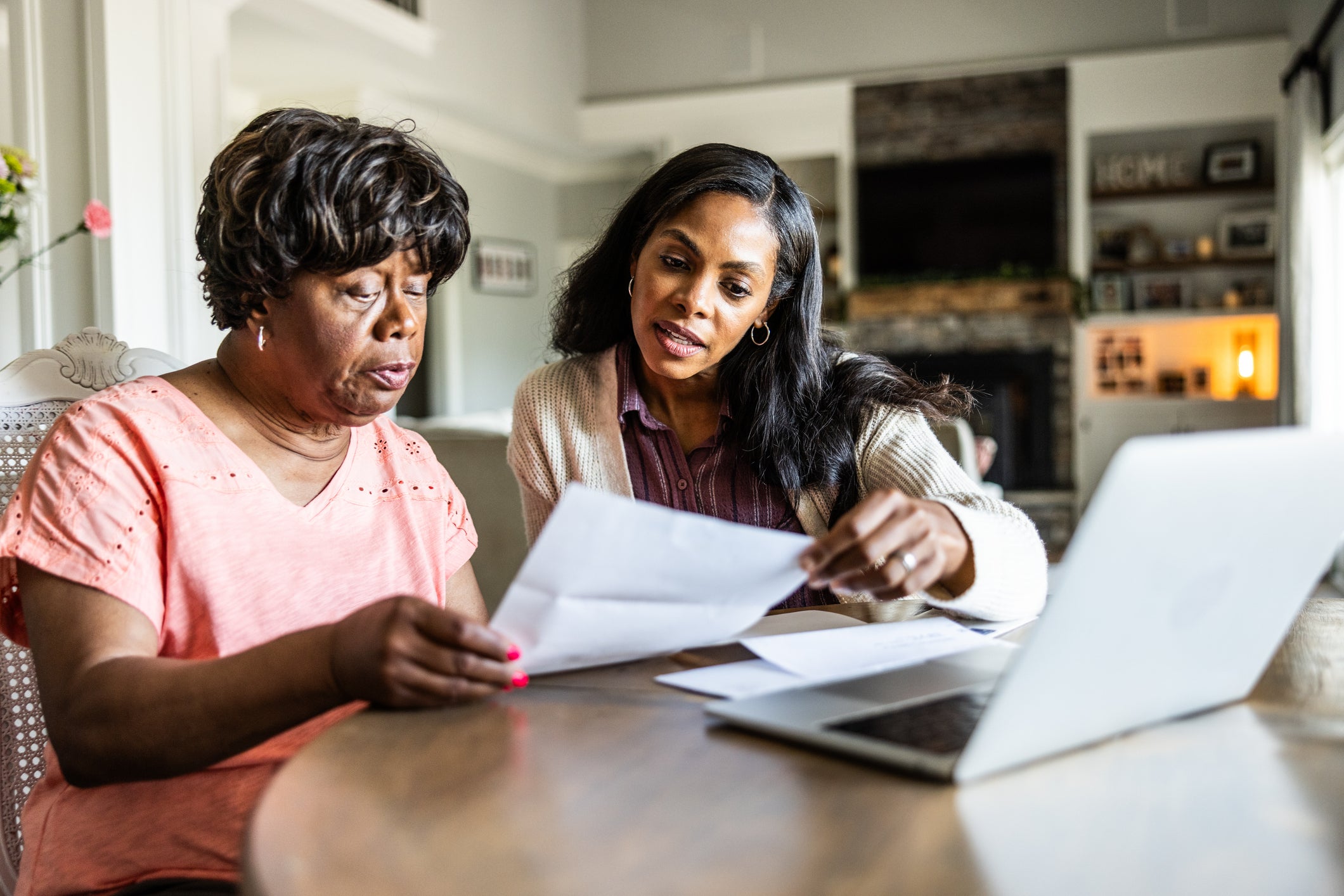 Adult daughter helping her senior mother look over bills at home