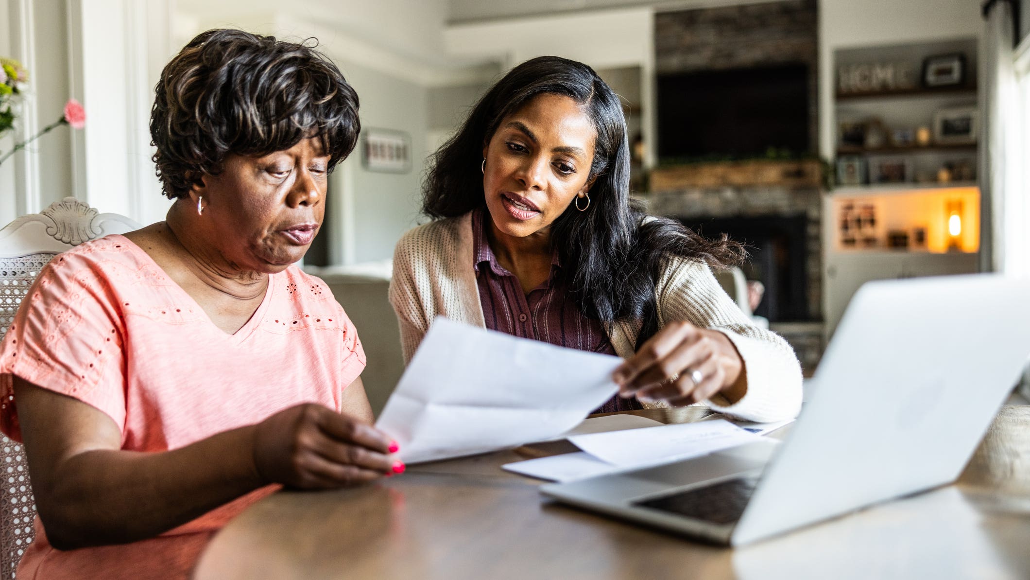 Adult daughter helping her senior mother look over bills at home