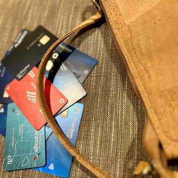A pile of credit cards beside a brown purse