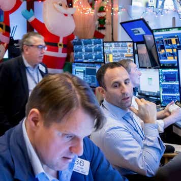 Three traders looking at various monitors with Christmas decorations in the background.