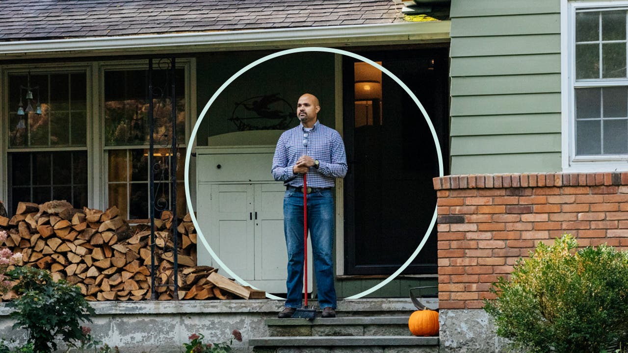 Person standing on front porch while holding a broom