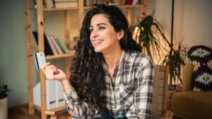 Portrait of a happy young woman using credit a card for online shopping at home