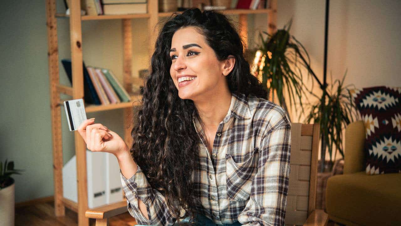 Portrait of a happy young woman using credit a card for online shopping at home