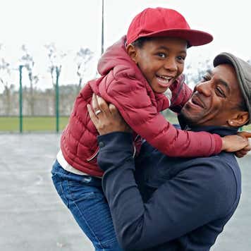 A father and son play in a park together.