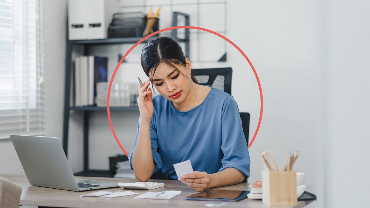Young woman reviewing her finances at home with an illustrated orange circle behind her.