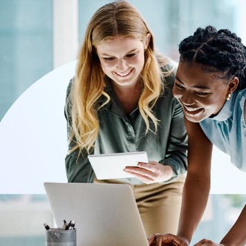 Two women look at a computer screen.