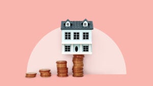 photo illustration - house balanced on stack of coins - pink background