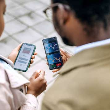 A man and woman check their crypto investments on their phones.