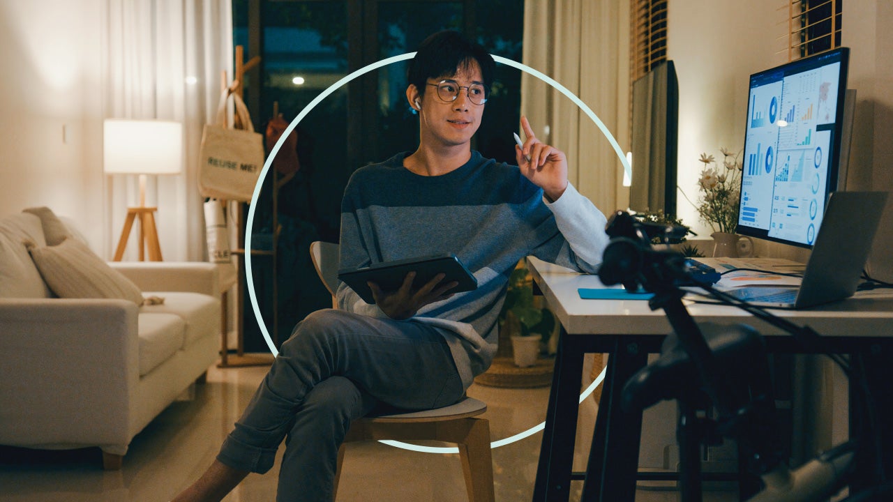 Person looking at charts on a computer monitor while holding a tablet.