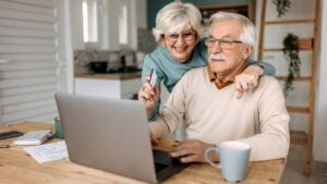 Old couple shopping online at home using laptop