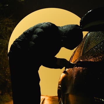 person in darkness trying to break into a vehicle