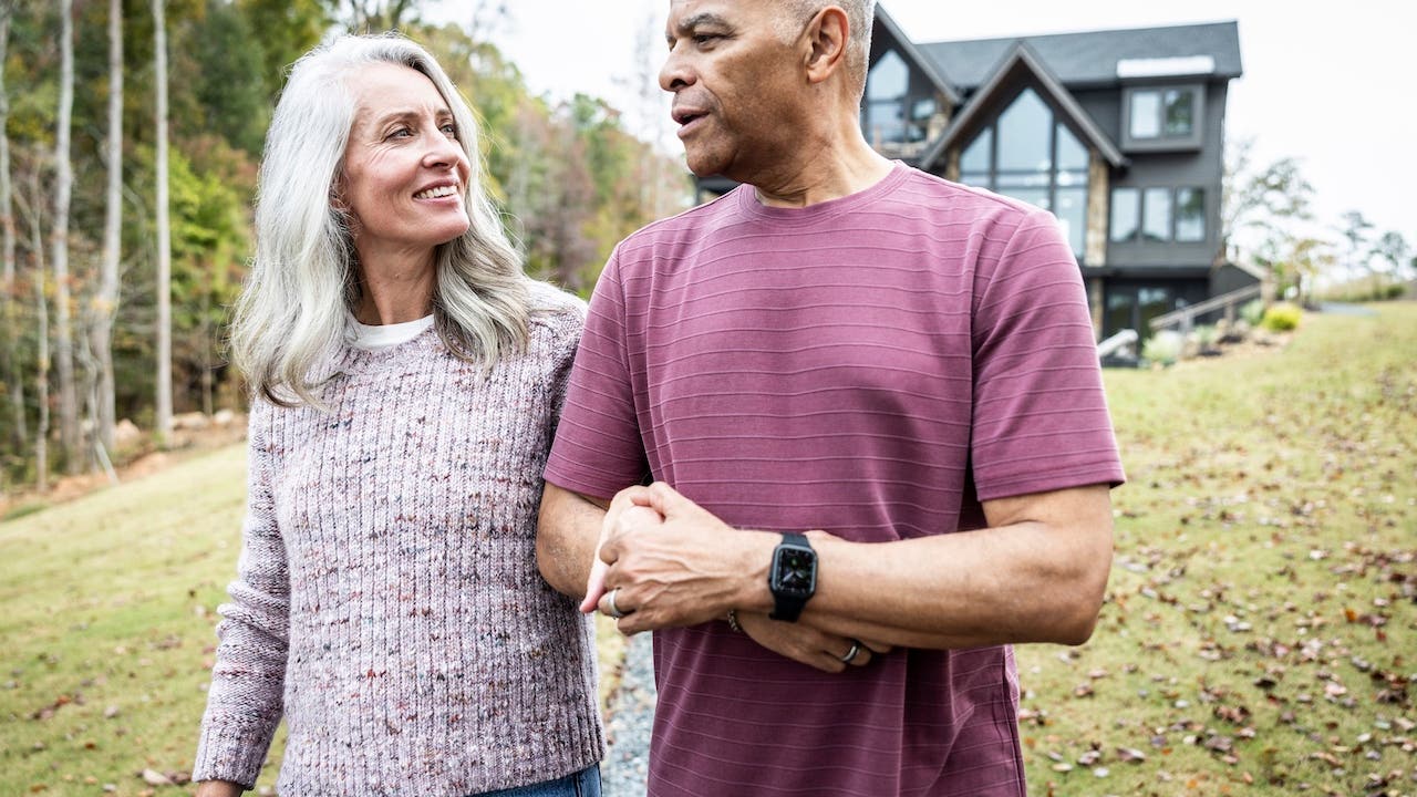 Older couple walking in front of their home