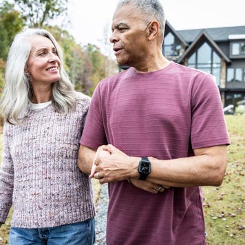 Older couple walking in front of their home