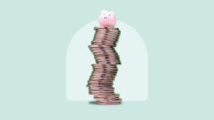 A piggybank resting atop a stack of coins on a green background.