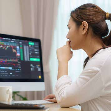 Person looking at computer monitor displaying stock data.