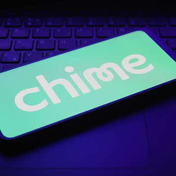 Smartphone displaying Chime logo on top of a laptop keyboard.