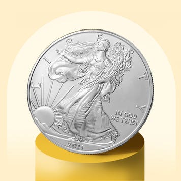 A silver coin sits on a gold pedestal.