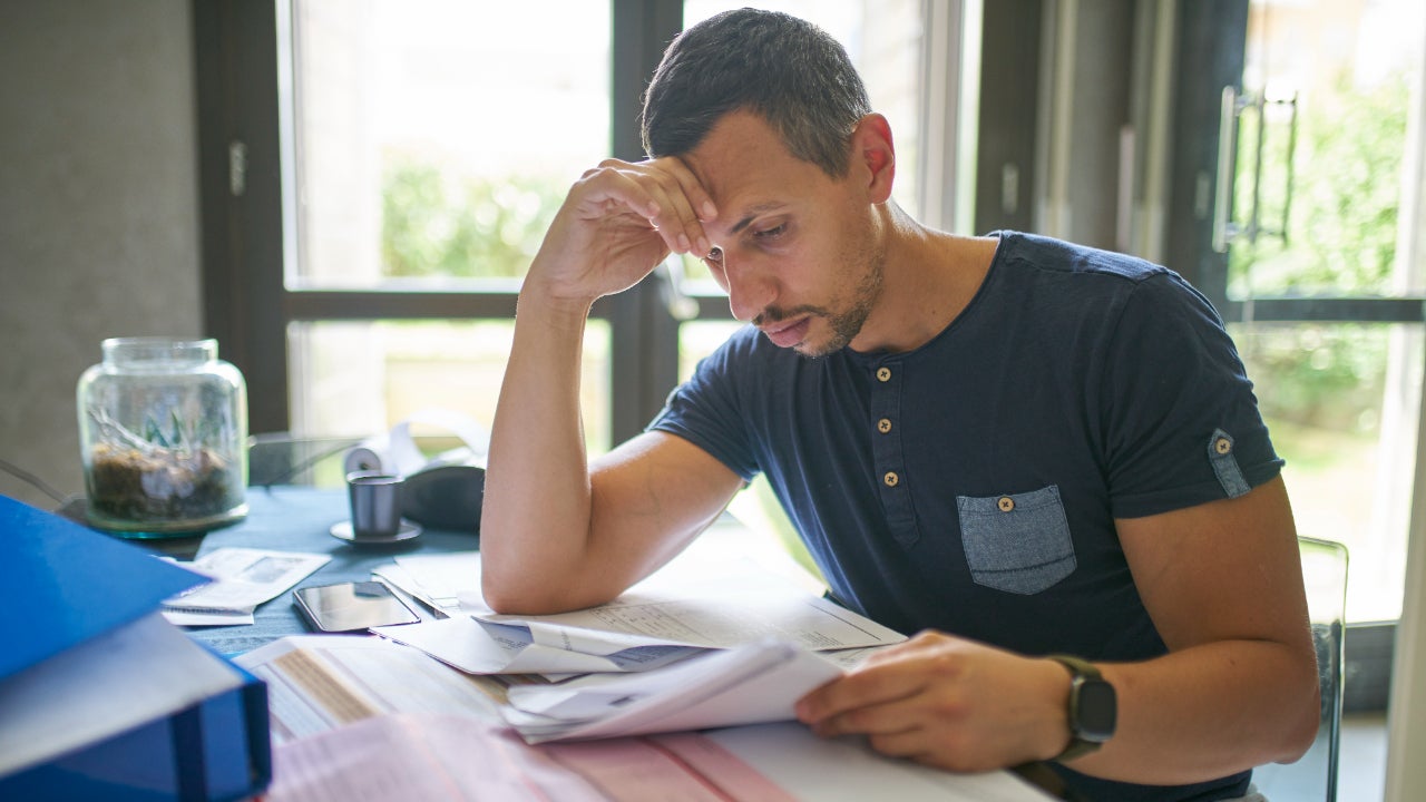 Man sits at a table reviewing a large array of paperwork.