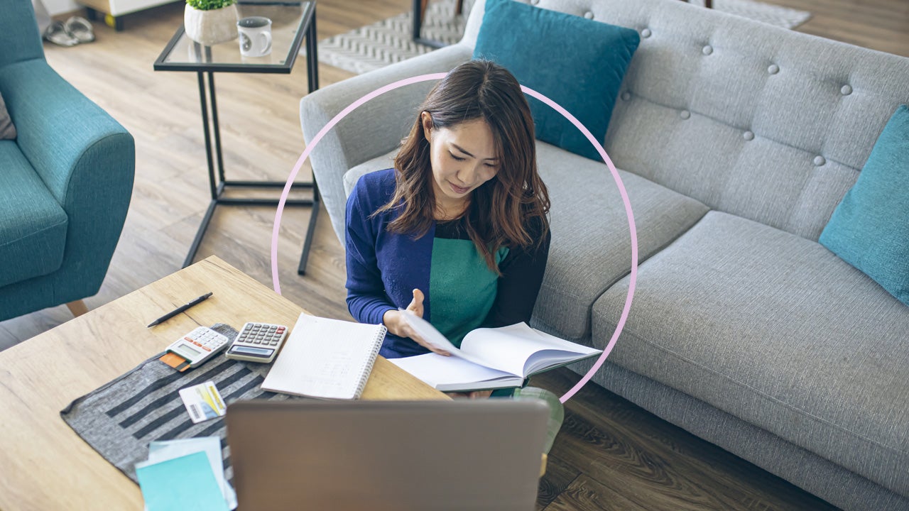 Woman looking through a journal while sitting on the floor in front of a coffee table and sofa
