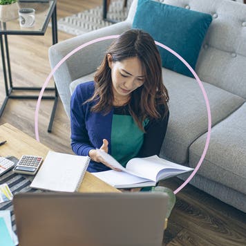 Woman looking through a journal while sitting on the floor in front of a coffee table and sofa