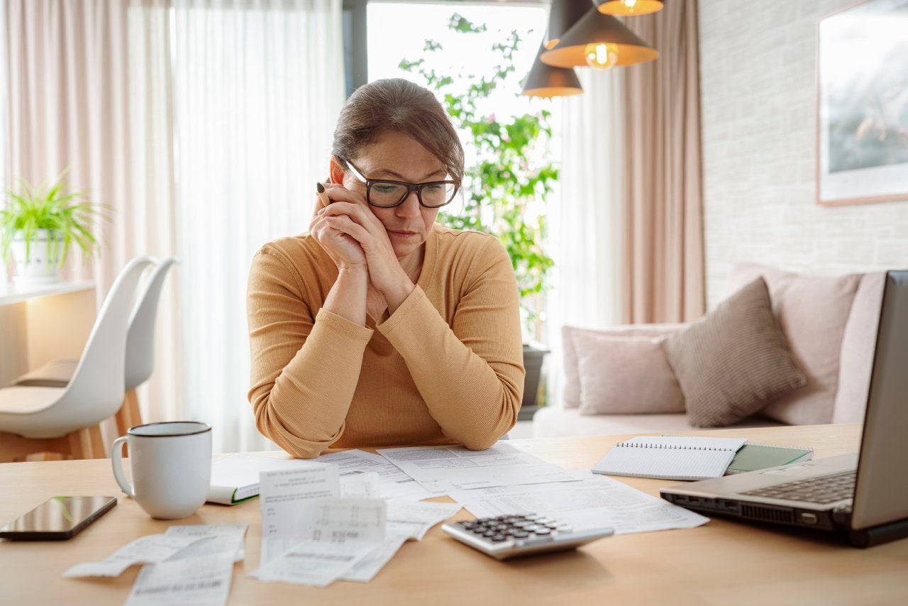 Mature woman contempling bills and tax papers at home