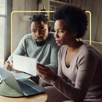 Two people sit at a computer and look at financial statements