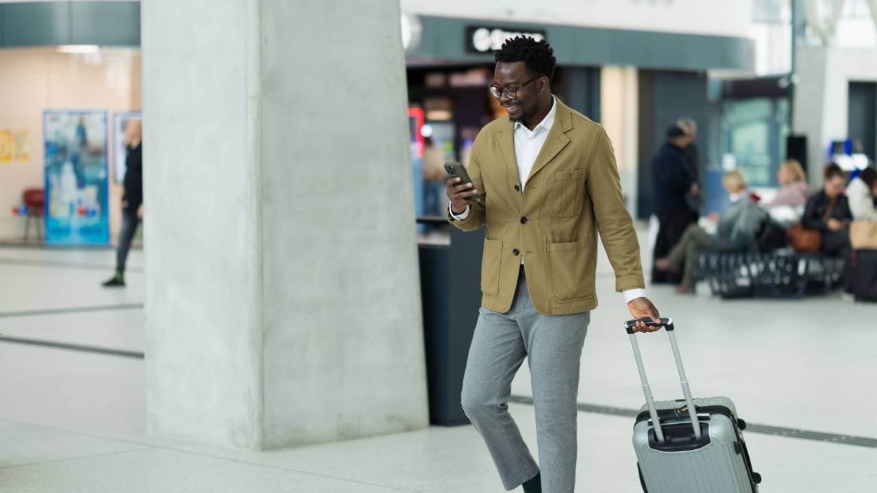 Business Professional Walking in Airport Terminal With Luggage