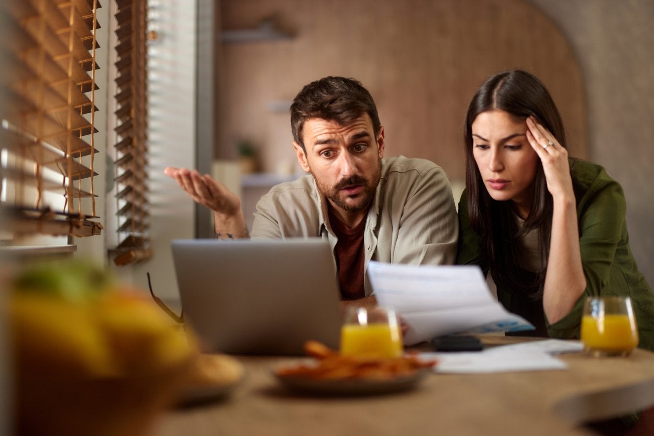 Displeased couple having problems with paying their bills online at home.