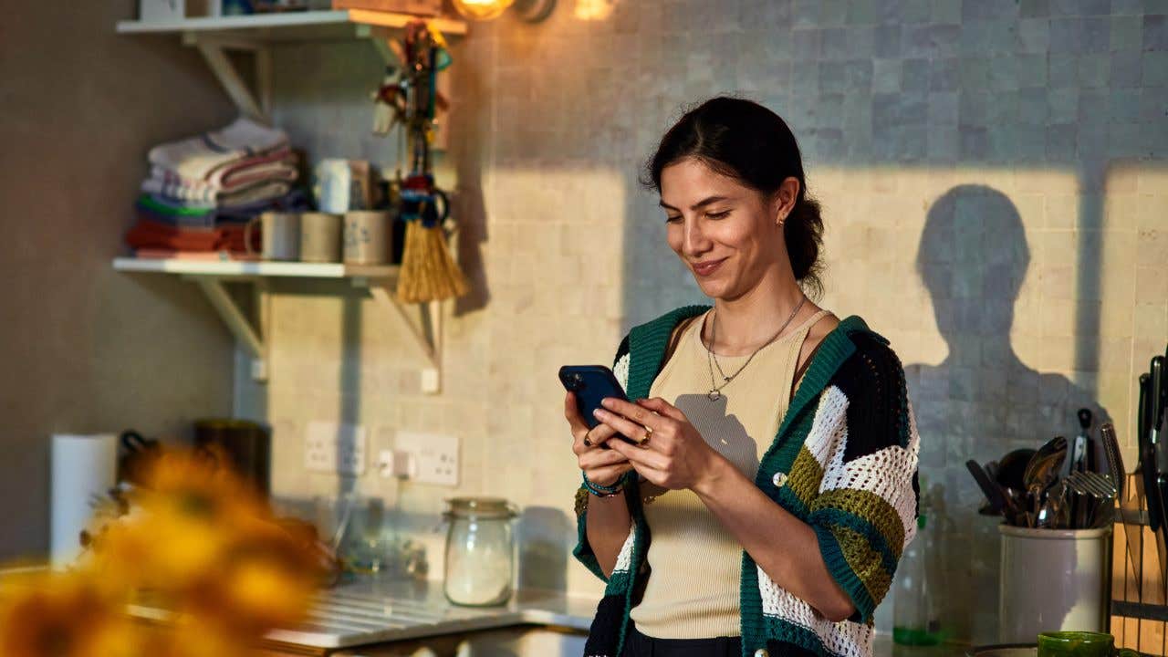 woman smiling at her phone in a kitchen