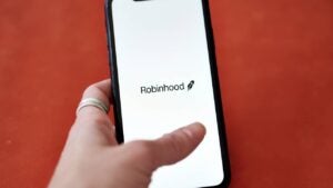 A hand holding a phone with the Robinhood logo on it.