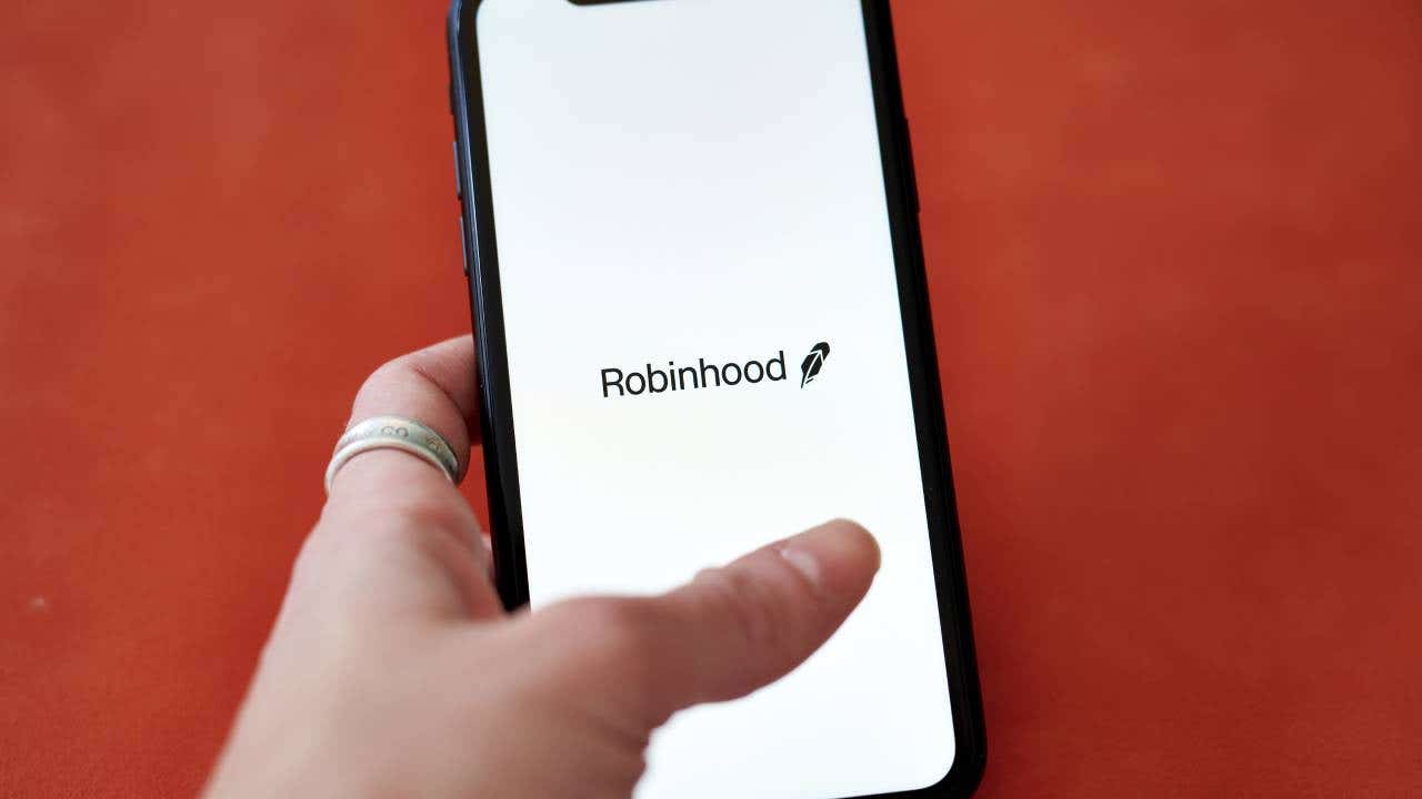 A hand holding a phone with the Robinhood logo on it.