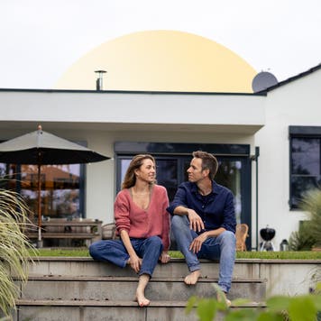 Couple sits in front of home