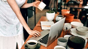 Cropped shot of a woman standing and using her laptop in her pottery workshop