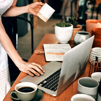 Cropped shot of a woman standing and using her laptop in her pottery workshop