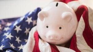 A smiling pink piggy bank resting atop a U.S. flag